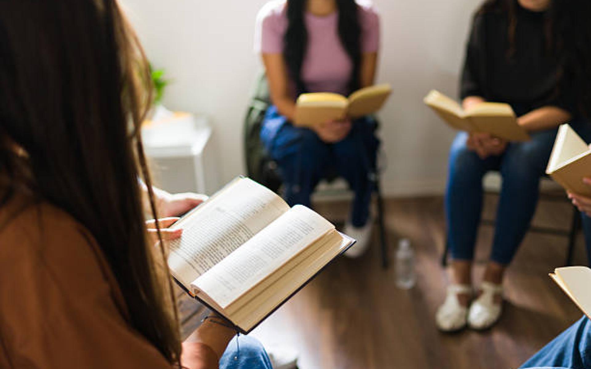 Personen in einer Runde mit Buch in Händen